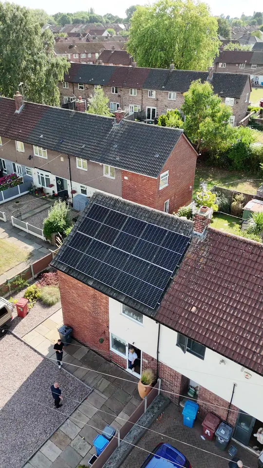 Full-width solar array on the front roof of an end-of-terrace house, customer at the door
